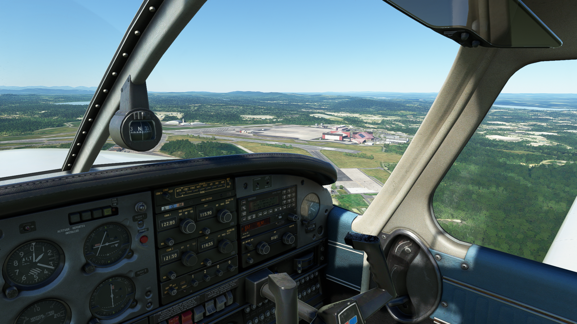 Light aircraft cockpit in flight looking across an airifeld